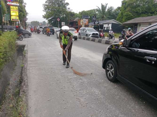 Polisi Bersihkan Ceceran Pasir dan Kerikil Yang Berada di Tengah Jalan